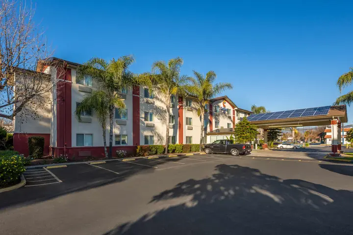 The hotel's parking lot in front of the three-story building, with palm trees and the covered entrance